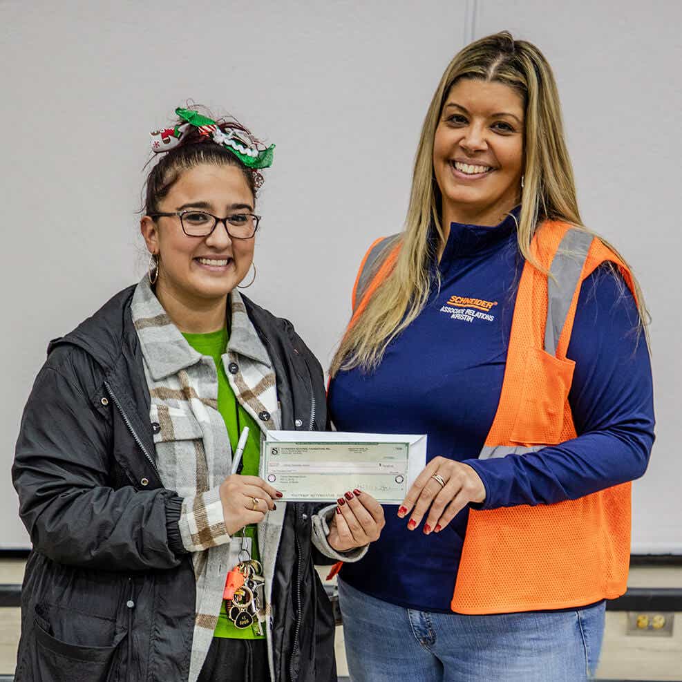 A Schneider associate presenting a check to a recipient of a financial donation from the Schneider Foundation.