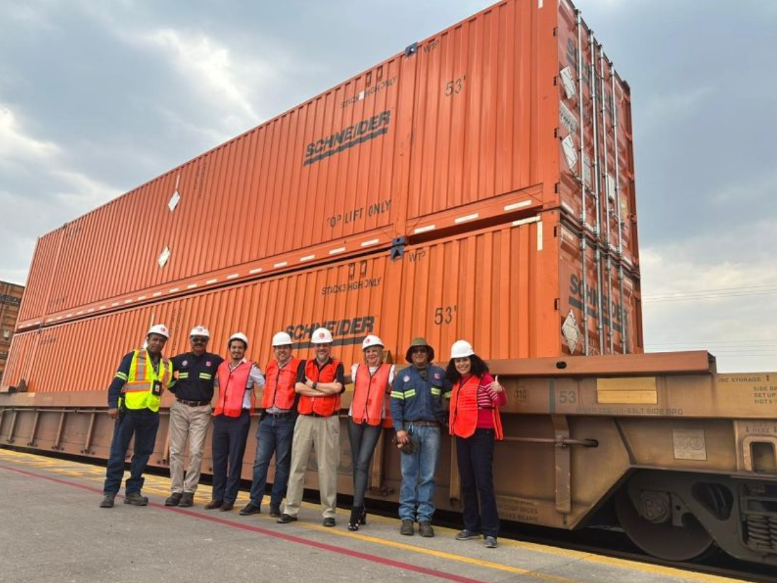 CPKC employees standing in front of Schneider shipping containers